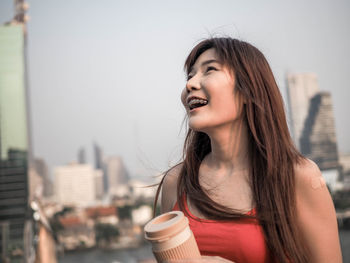 Portrait of smiling young woman with coffee in city