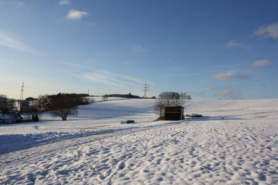 Scenic view of snow covered field against sky