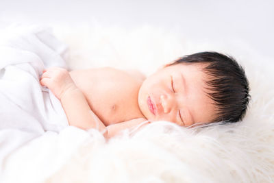 A newborn cute baby. newborn child wearing white cotton fluffy. infant baby girl sleeping in bed.