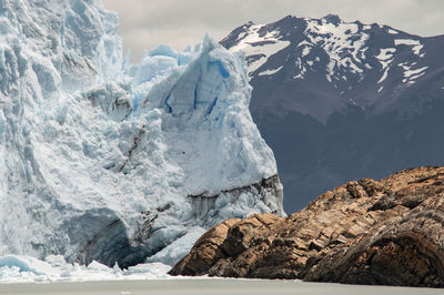 Scenic view of glacier with snow capped mountains in the background.