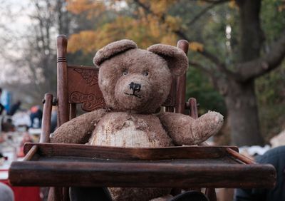 Close-up of old teddy bear on chair outdoors