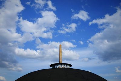 Low angle view of communications tower against cloudy sky