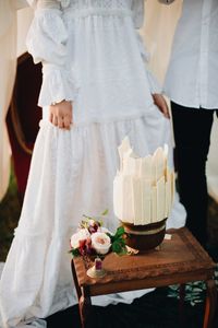Midsection of bride and groom standing by table at home 