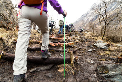 Low angle view of hikers climbing mountain against sky