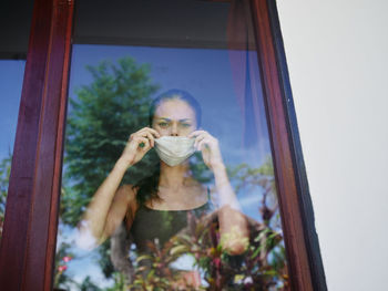 Portrait of young woman drinking glass window