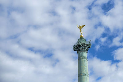 Low angle view of angel statue against cloudy sky