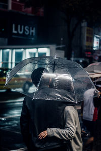 Man holding umbrella on wet street in rainy season