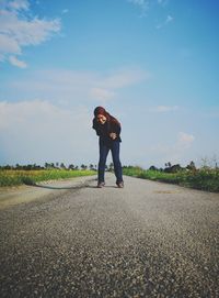 Full length of woman bending on road against sky