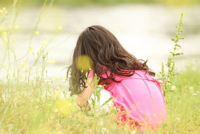 Rear view of girl with flowers on field