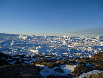 Aerial view of snowcapped mountains against clear blue sky