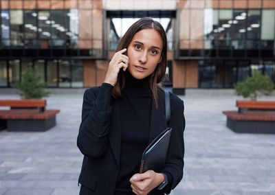 Portrait of young woman standing in city