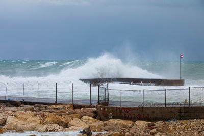 Waves breaking on rocks against sky