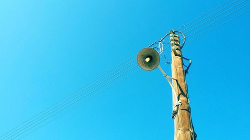 Low angle view of electricity pylon against blue sky