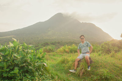 Woman sitting on mountain against sky