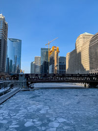 Modern buildings by river against sky in city