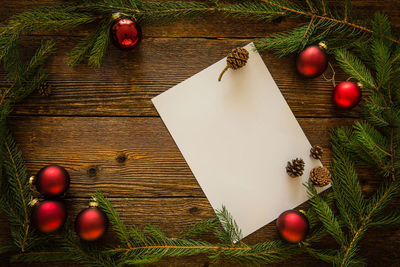 High angle view of pine needles with blank paper on wooden table