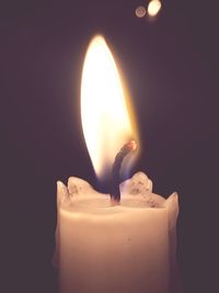 Close-up of lit candle over black background