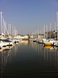 Sailboats moored on harbor against sky