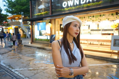 Woman looking away while standing in illuminated city