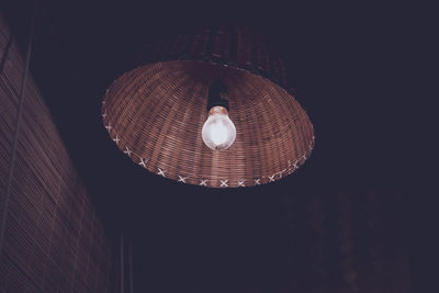 Low angle view of light bulb with wicker protection hanging from ceiling