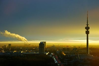 Olympic tower amidst buildings against sky during sunrise