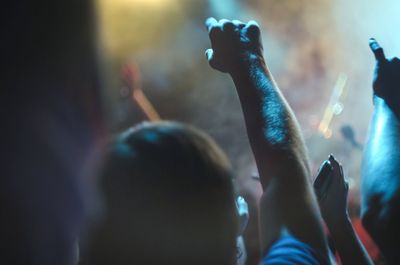 People with arms raised enjoying at music concert