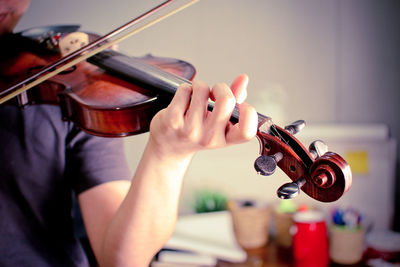 Midsection of man playing violin while standing at home