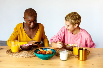 Lesbian couple having breakfast on table at home