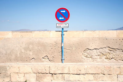 Low angle view of road sign against clear blue sky