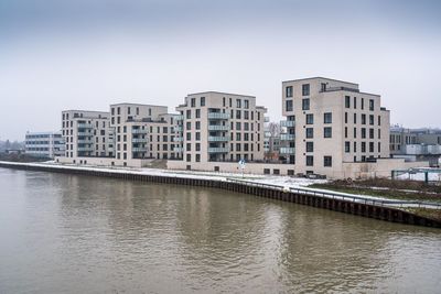 Bridge over river by buildings against sky in city