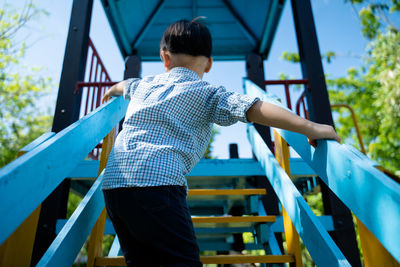 Rear view of boy on slide in playground