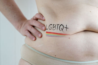 Woman with hand on waist and belly painted with rainbow flag lgbtq