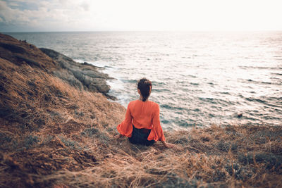 Rear view of woman sitting on mountain