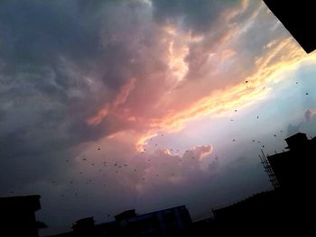 Low angle view of silhouette buildings against dramatic sky