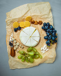 Camembert and brie cheese on a rustic background with grapes, nuts, jam and cracker, italian food