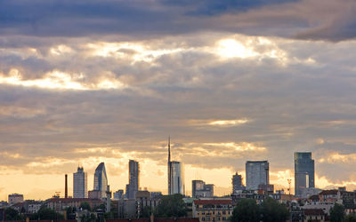 Cityscape against cloudy sky during sunset