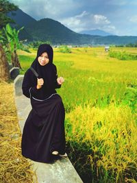 Young woman wearing burka while sitting on retaining wall