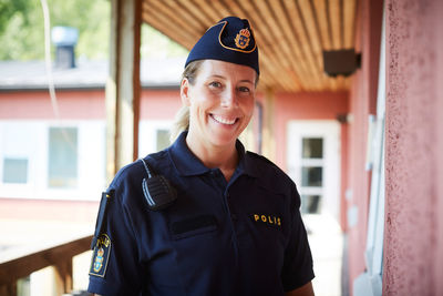 Portrait of smiling policewoman wearing cap standing in balcony at police station