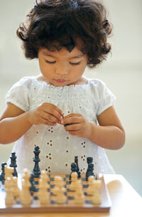 Cute girl playing with chessboard