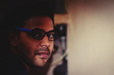 Close-up portrait of young man wearing eyeglasses at home