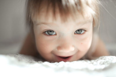 Funny girl toddler with a smile lying on the bed, close-up, concept happy happy childhood, 