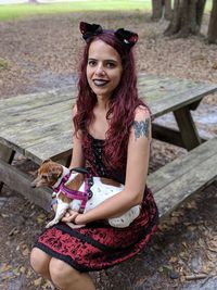 Portrait of woman with dog sitting on bench