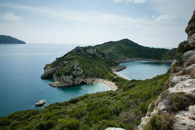 Scenic view of sea by mountains against sky