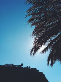 Low angle view of silhouette tree by mountain against clear blue sky