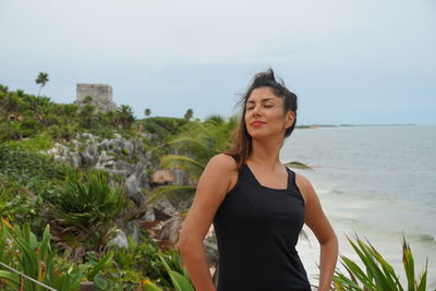 Beautiful young woman standing on land against sky