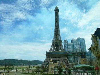 Low angle view of skyscrapers against cloudy sky