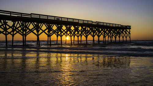 Bridge over sea against clear sky during sunset