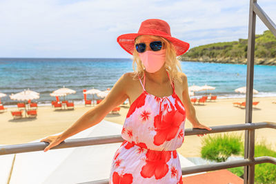 Woman wearing mask standing against sea