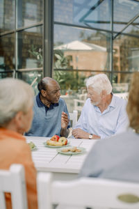 Senior men talking to each other while sitting at dining table