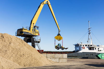 Large crane lifting bulldozer in harbour